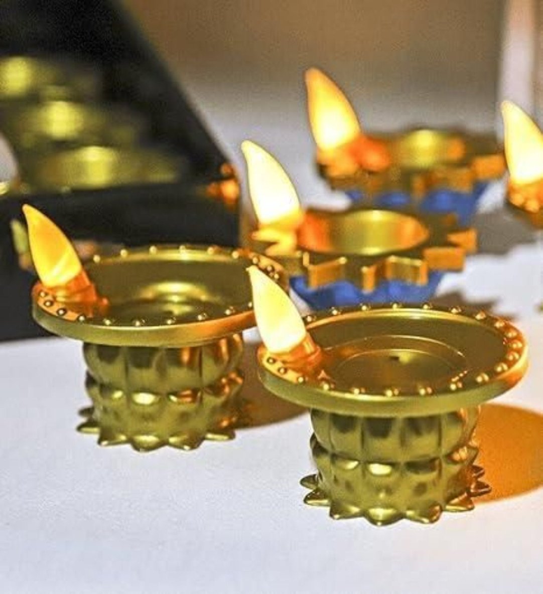 A set of gold-colored Water Pouring Diya LED Lights with lit wicks, creating a warm, enchanting glow.