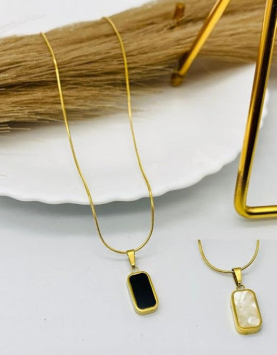 Gold plated stainless steel necklace chain displayed on a white plate with a golden object in the background.