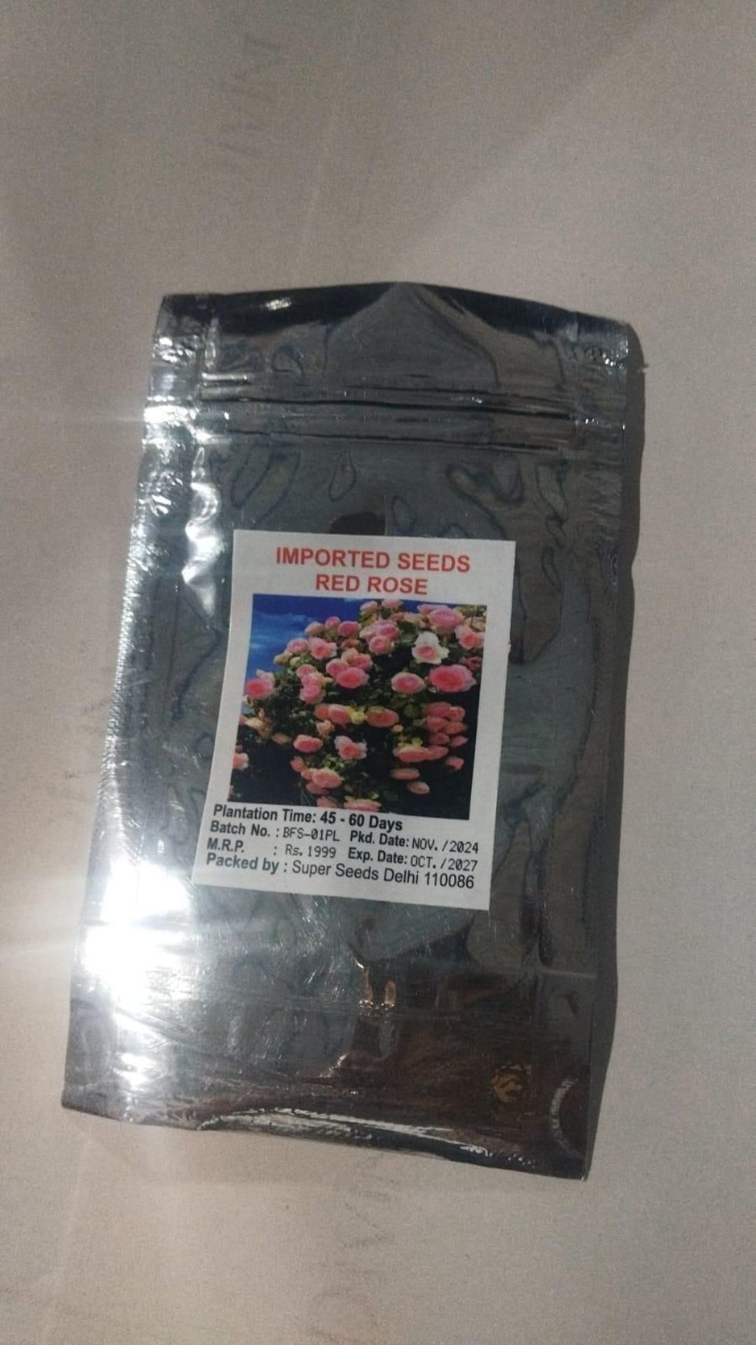 Black package of imported seeds with a label featuring flowers on a light gray background