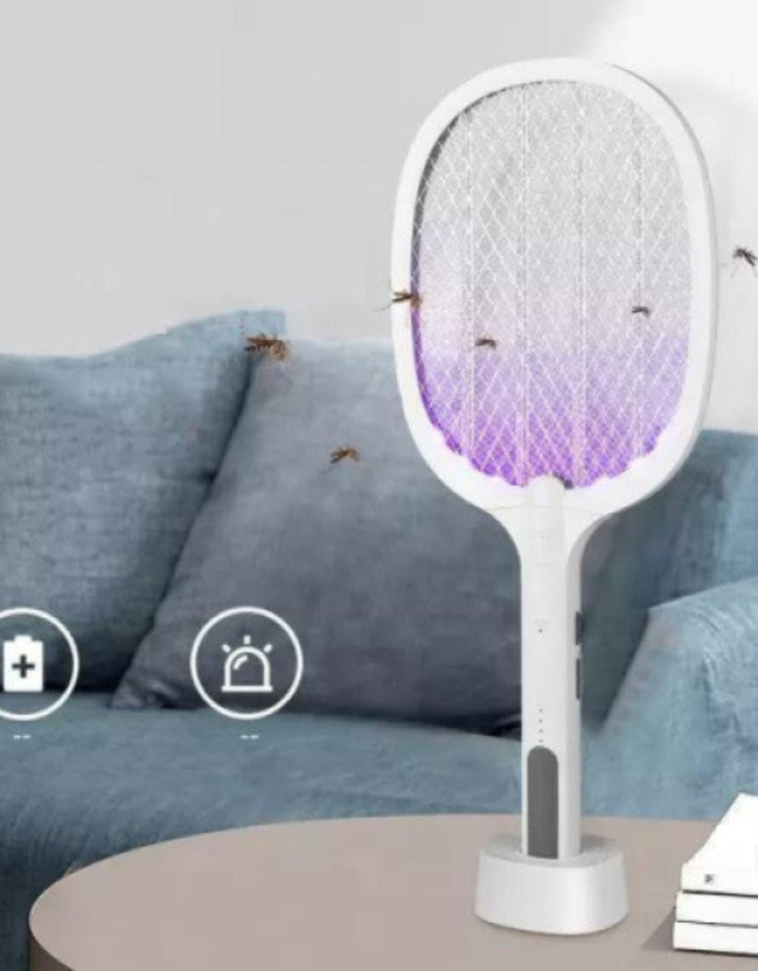 Electronic fly swatter with purple light on a table against a gray couch background