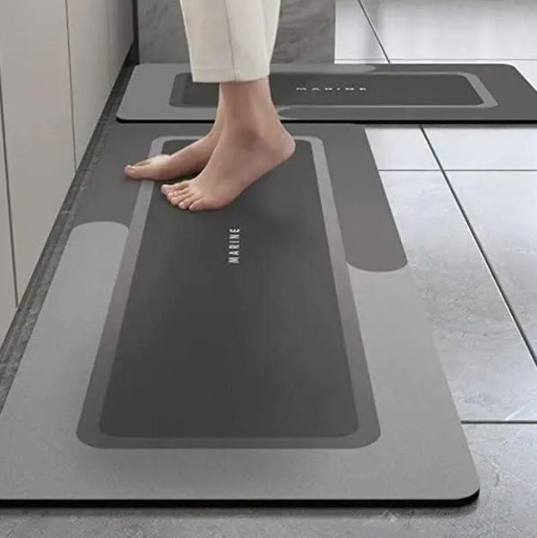 Person stepping onto a gray anti-fatigue mat with 'Marime' branding in a kitchen setting.