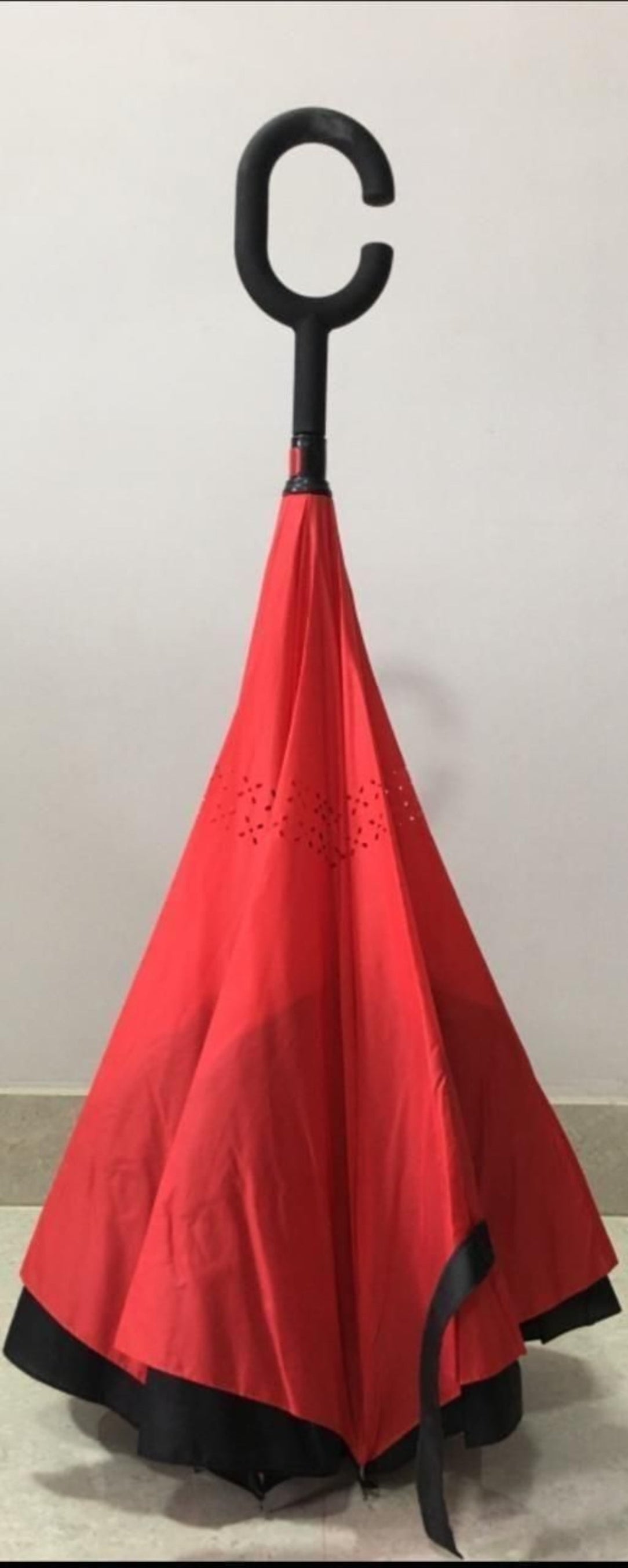 Red umbrella with a black handle on a white background