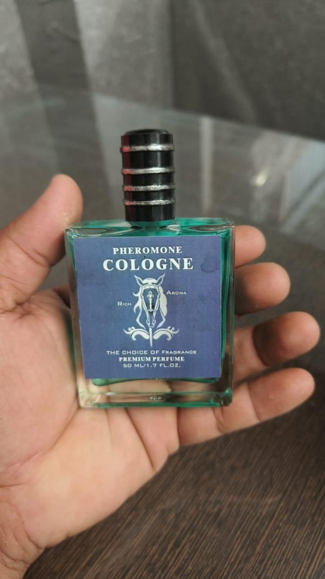 Hand holding a bottle of 'Pheromone Cologne' with a blue label.