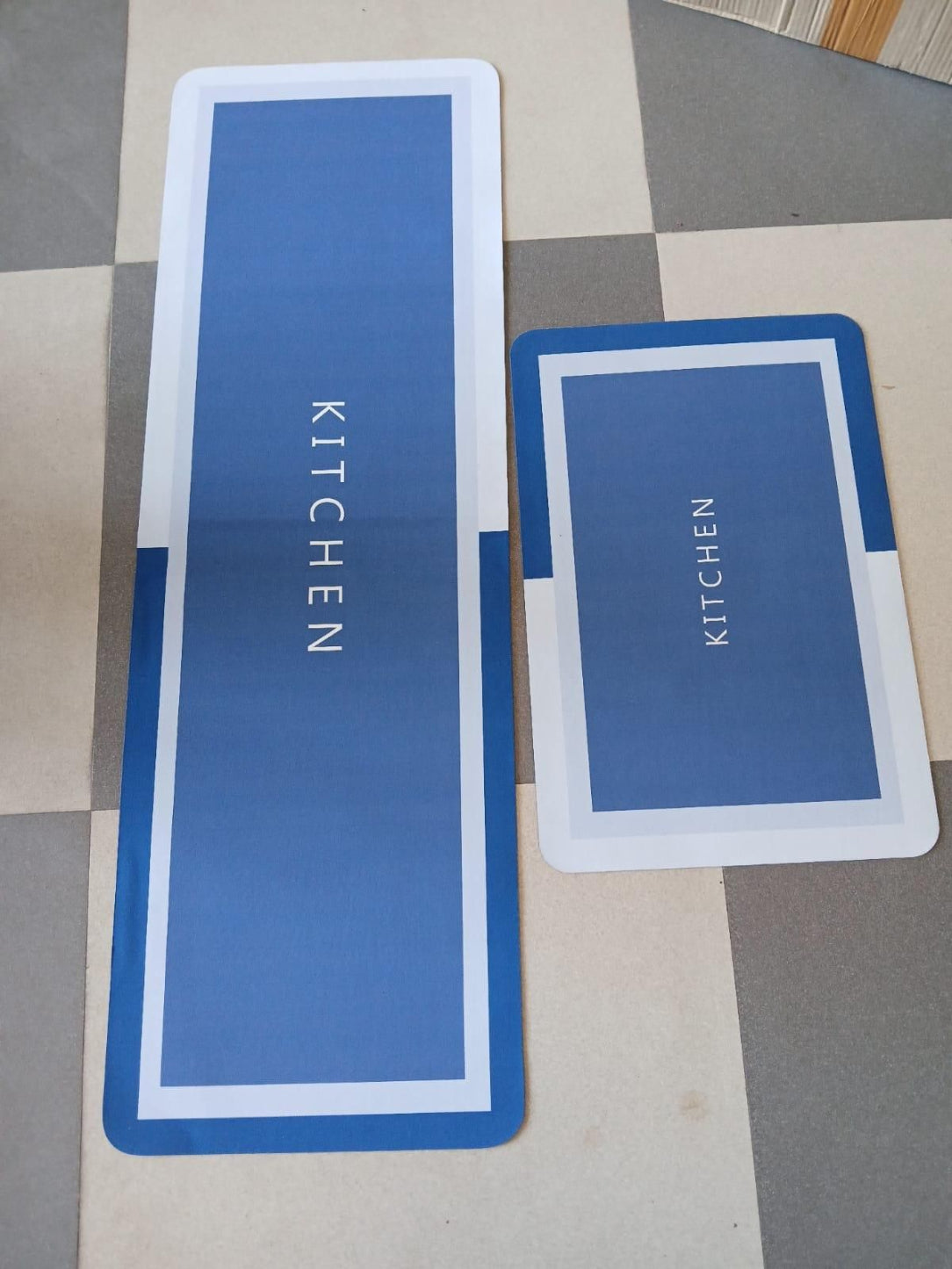 Two blue placemats with 'KITCHEN' text on a checkered floor.
