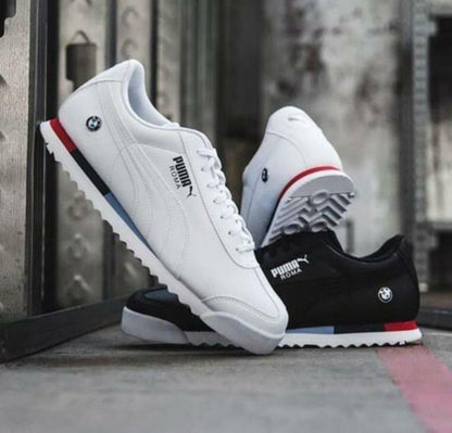 White, black, and red Puma sneakers on a textured surface