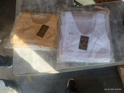 Two vests, one brown and one white, on a dark surface with visible brand labels.