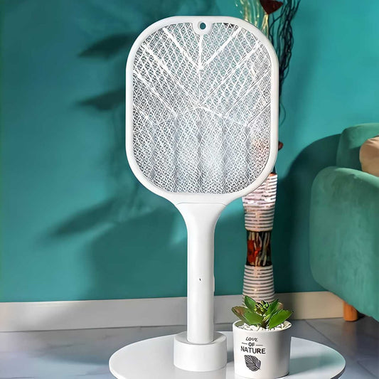 A white mosquito killer racket with LED light standing on a round base, placed in a home environment setting.