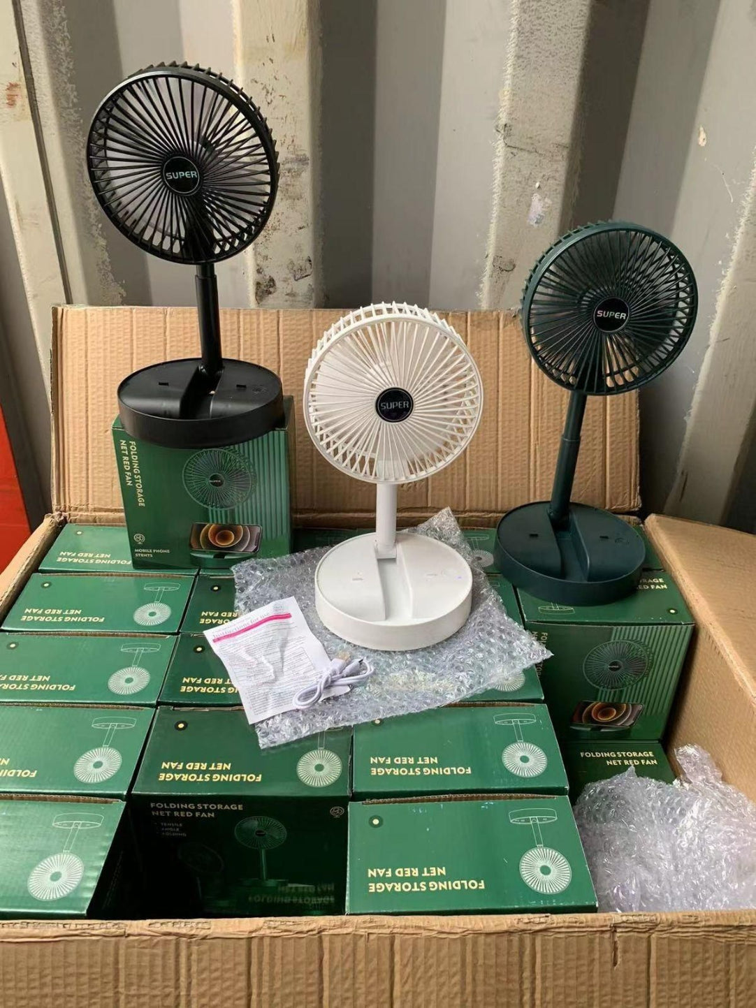 Tabletop fans and boxes on a cardboard surface with a striped wall background