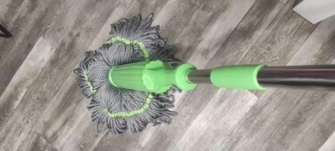 Mop with a green handle cleaning a wooden floor