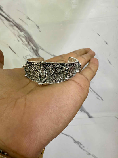 Silver bracelet held on a hand against a marble background