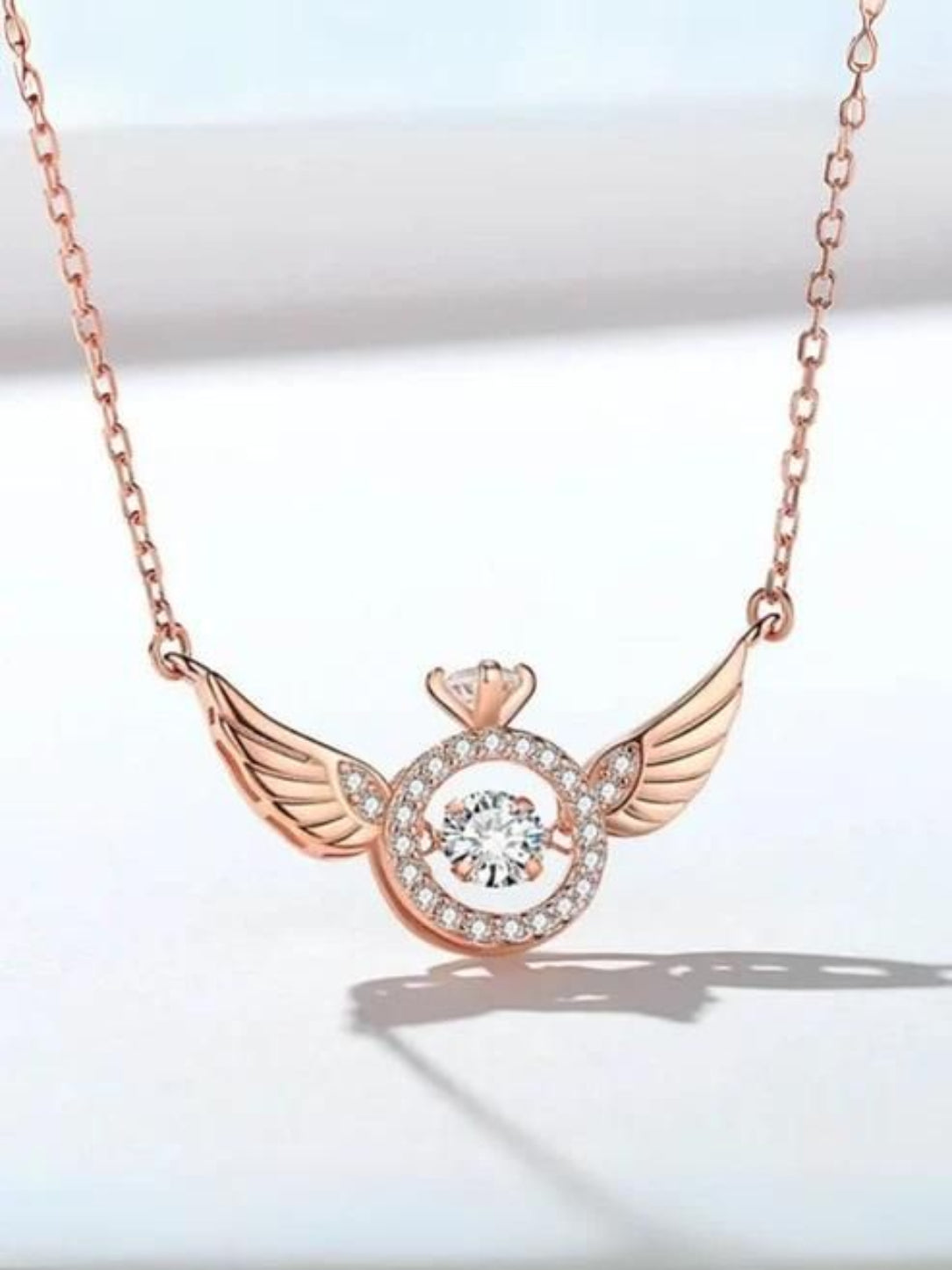 Rose gold necklace with a diamond pendant on a light background