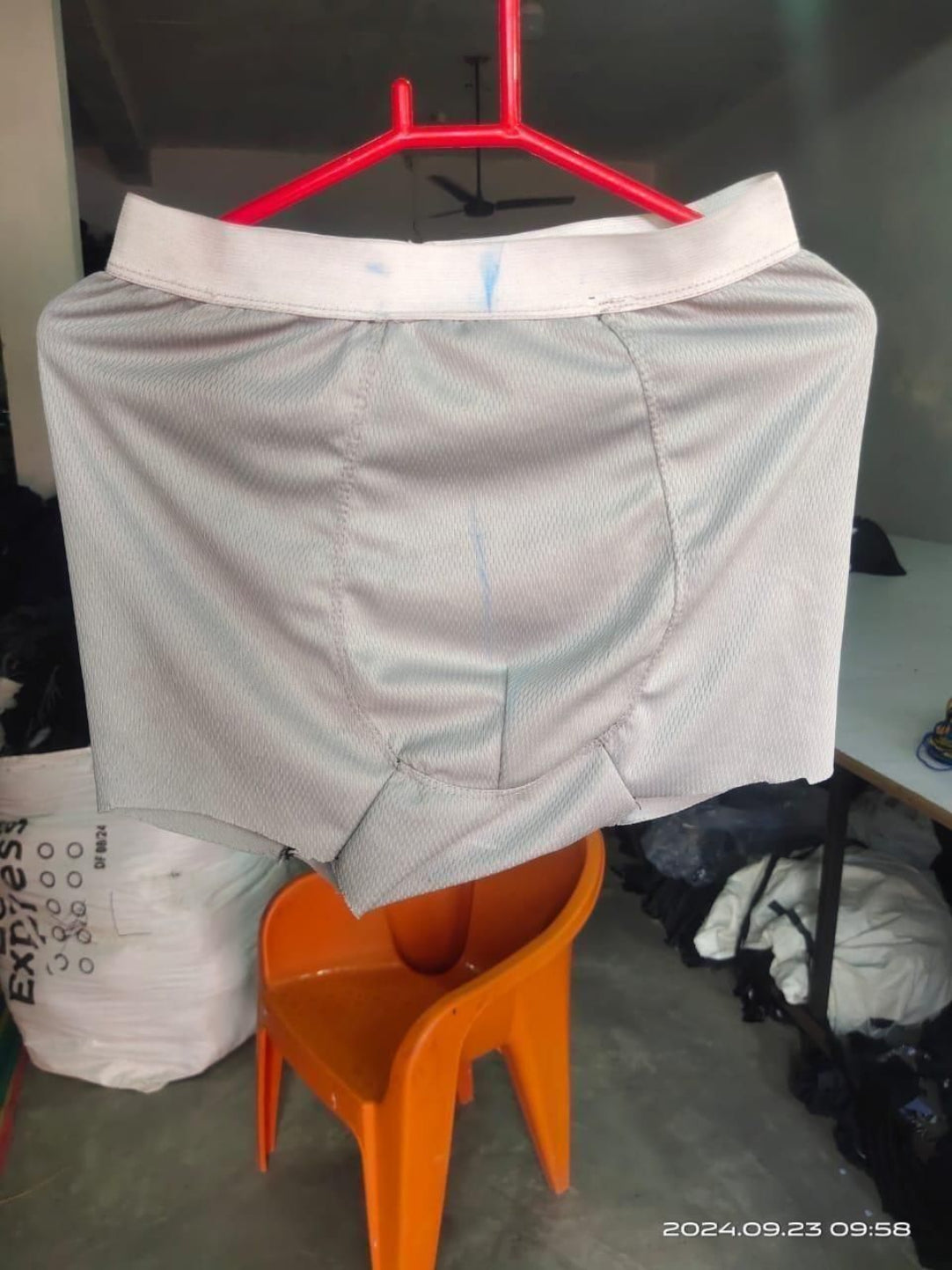 Gray athletic shorts on a red hanger with an orange chair and blurred background