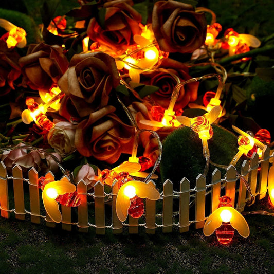 String lights designed to resemble honey bees with a warm brown color, placed on a fence in an outdoor setting, illuminating the area with a warm glow.