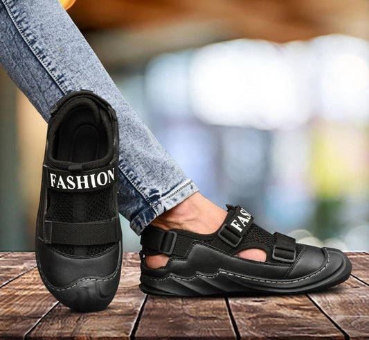 A person wearing casual jeans is showcasing a black sandal with the text 'FASHION' on it, indicating a casual dailywear sandal.