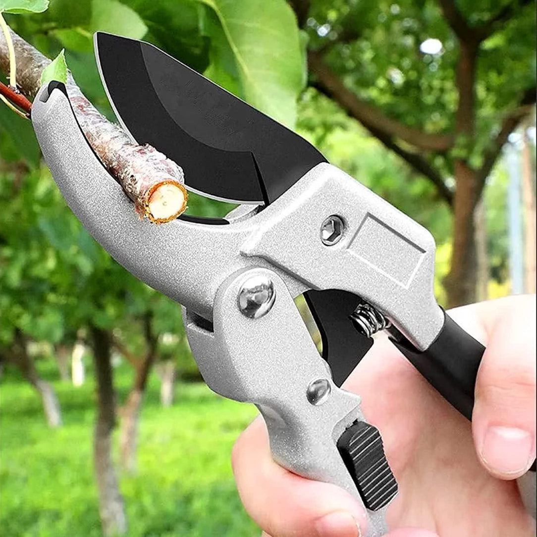 Gardening shears cutting a branch with a blurred green garden background