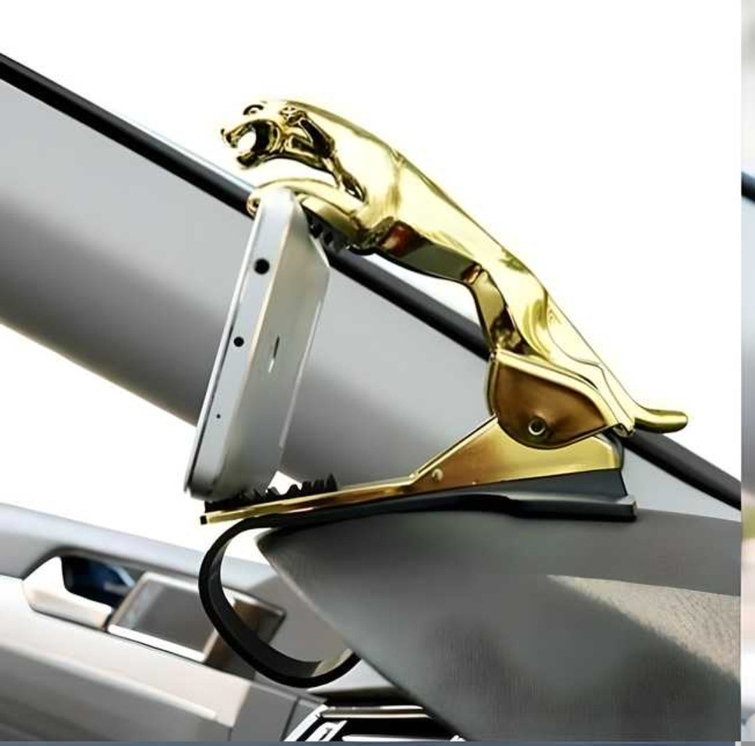 A gold-colored dashboard phone holder in the shape of a leopard, attached to a car dashboard with a mobile phone placed in it.