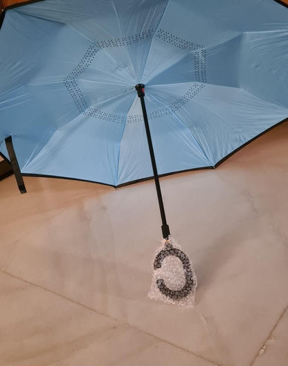Blue umbrella with a decorative pendant on a light-colored floor