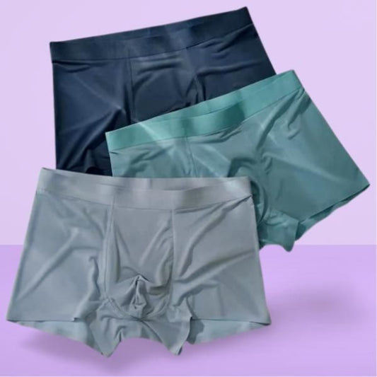 Three pairs of satin shorts in black, green, and gray on a purple background