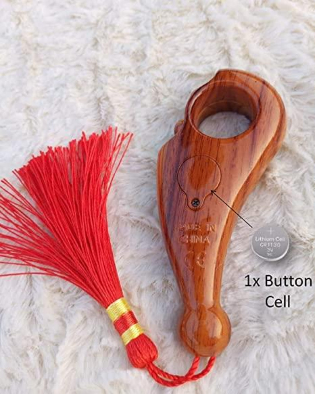 Wooden device with red tassel on a textured white background