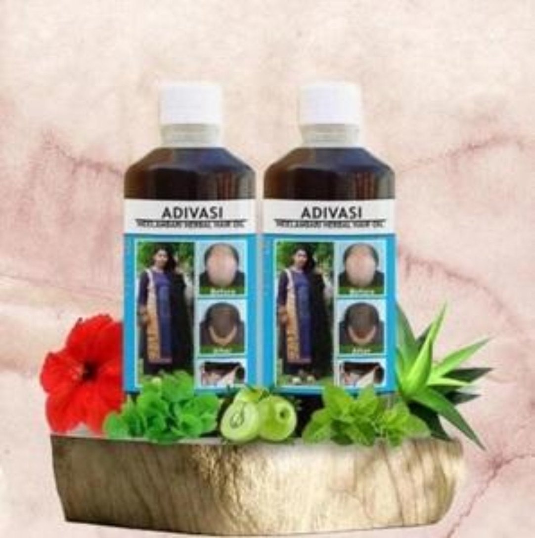 Two bottles of Adivasi Neelambari Herbal Hair Oil placed on a wooden surface with decorative flowers and herbs around them.