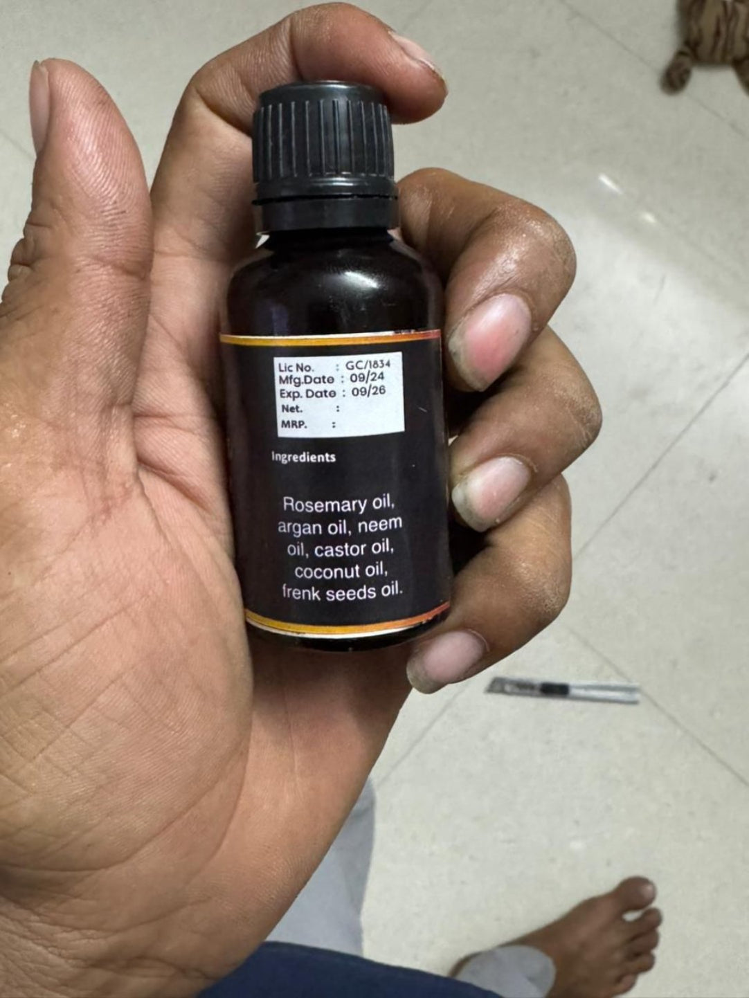 Hand holding a bottle of essential oil with a white background