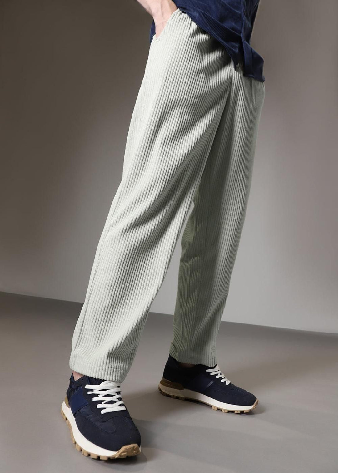 Person wearing light green striped pants and navy shoes on a plain background