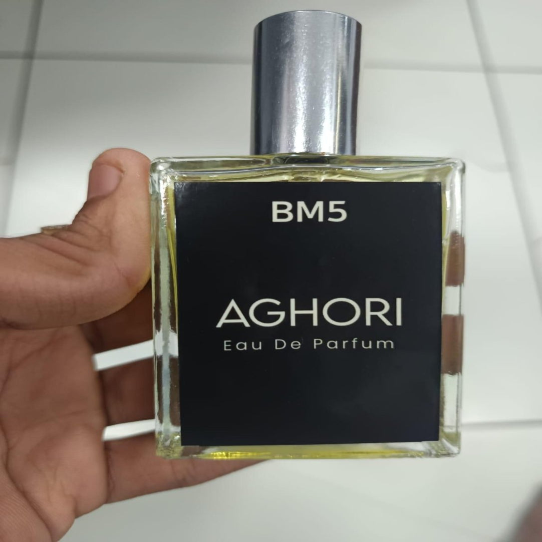 Aghori BM5 Eau De Parfum bottle held by a hand against a tiled wall background