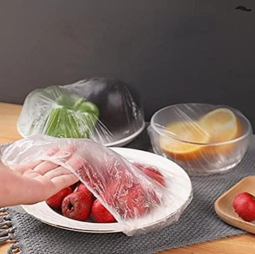 Fruits and vegetables wrapped in plastic wrap on a table with a gray background