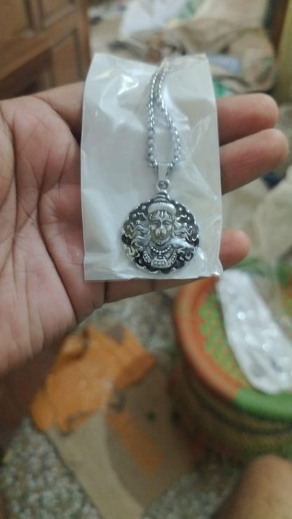 Silver necklace with pendant on a white card held in a hand, blurred background