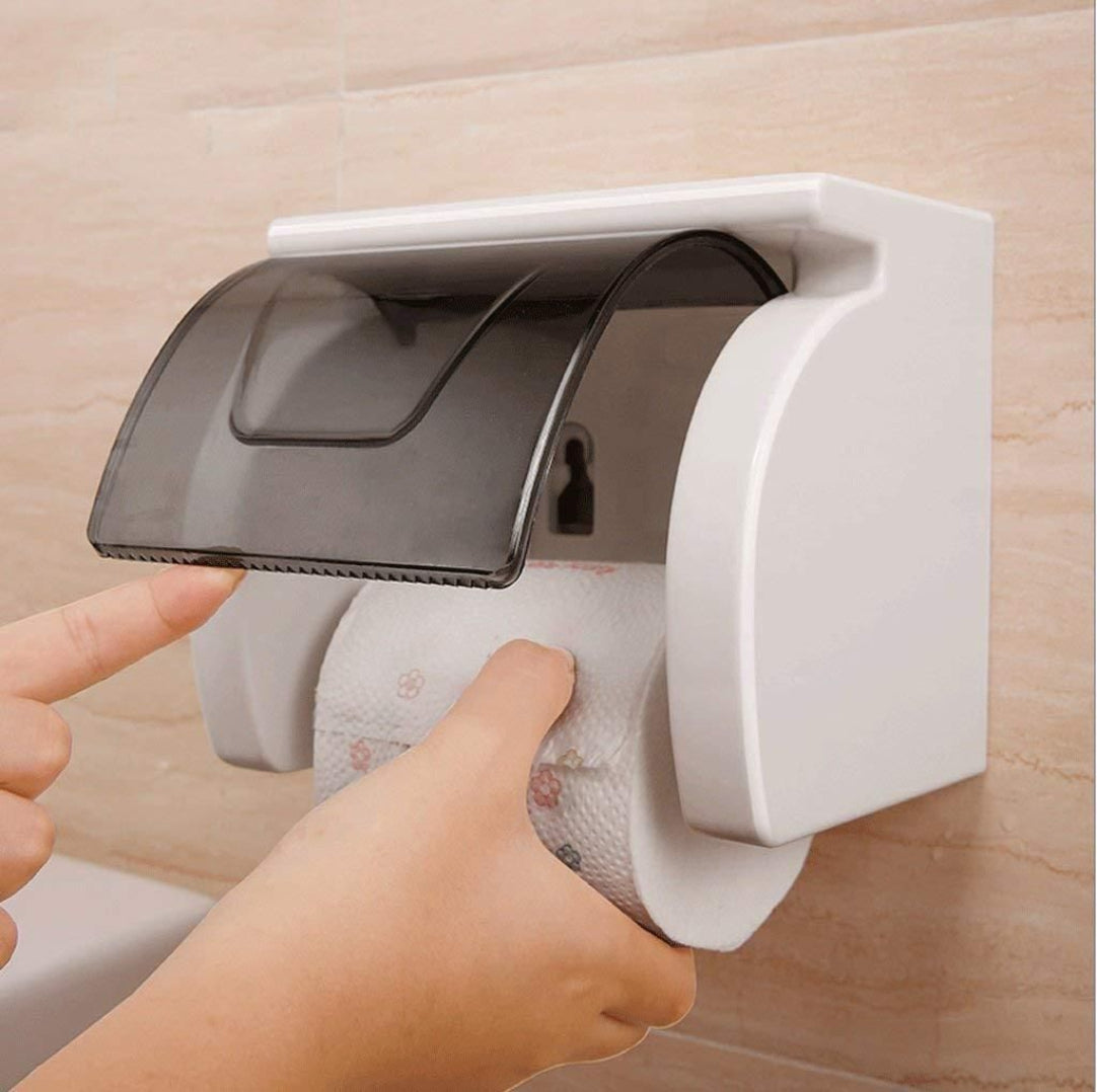 A white toilet paper holder with a self-adhesive roll holder mounted on a wall.