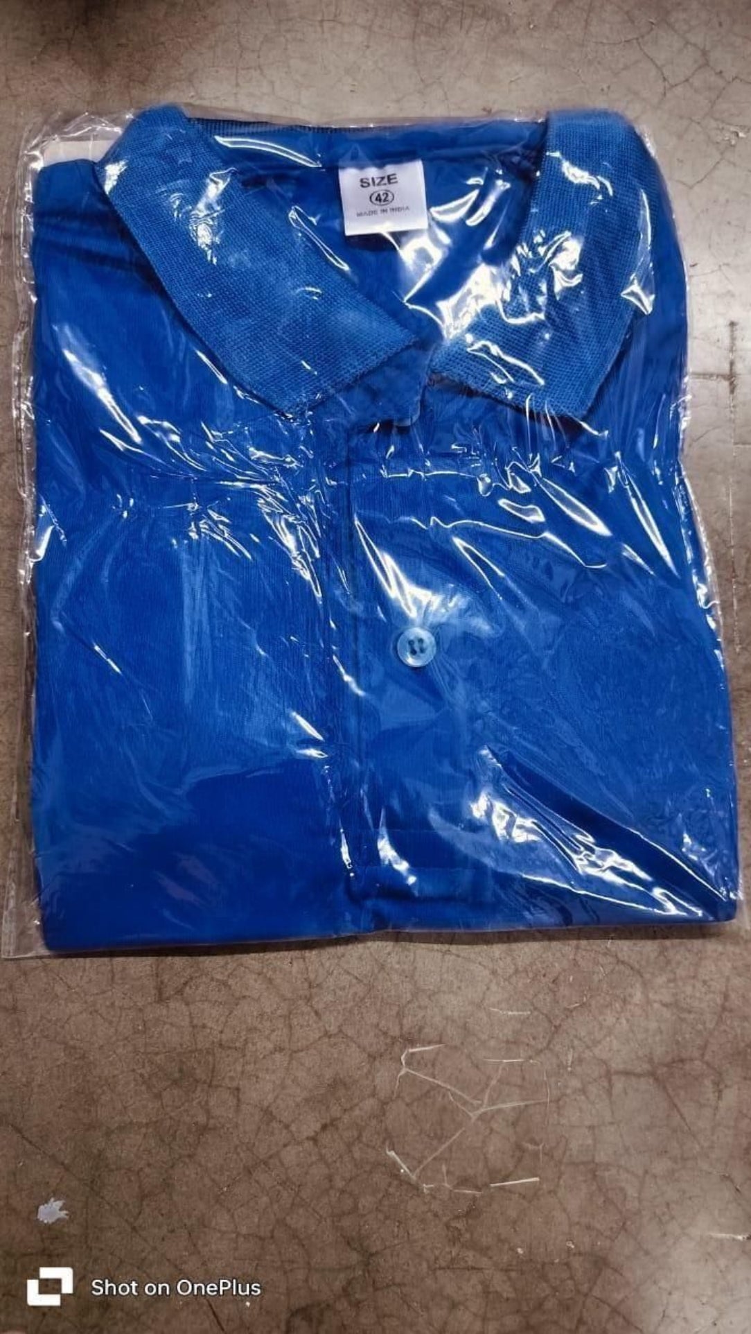 Blue shirt in clear plastic wrap on a brown surface