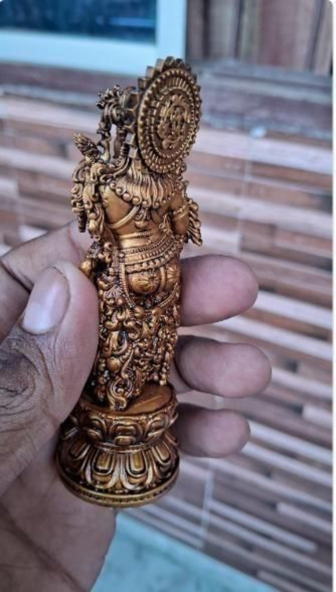 Decorative gold figurine held in a hand with a blurred background