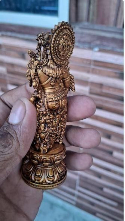 Decorative gold figurine held in a hand with a blurred background