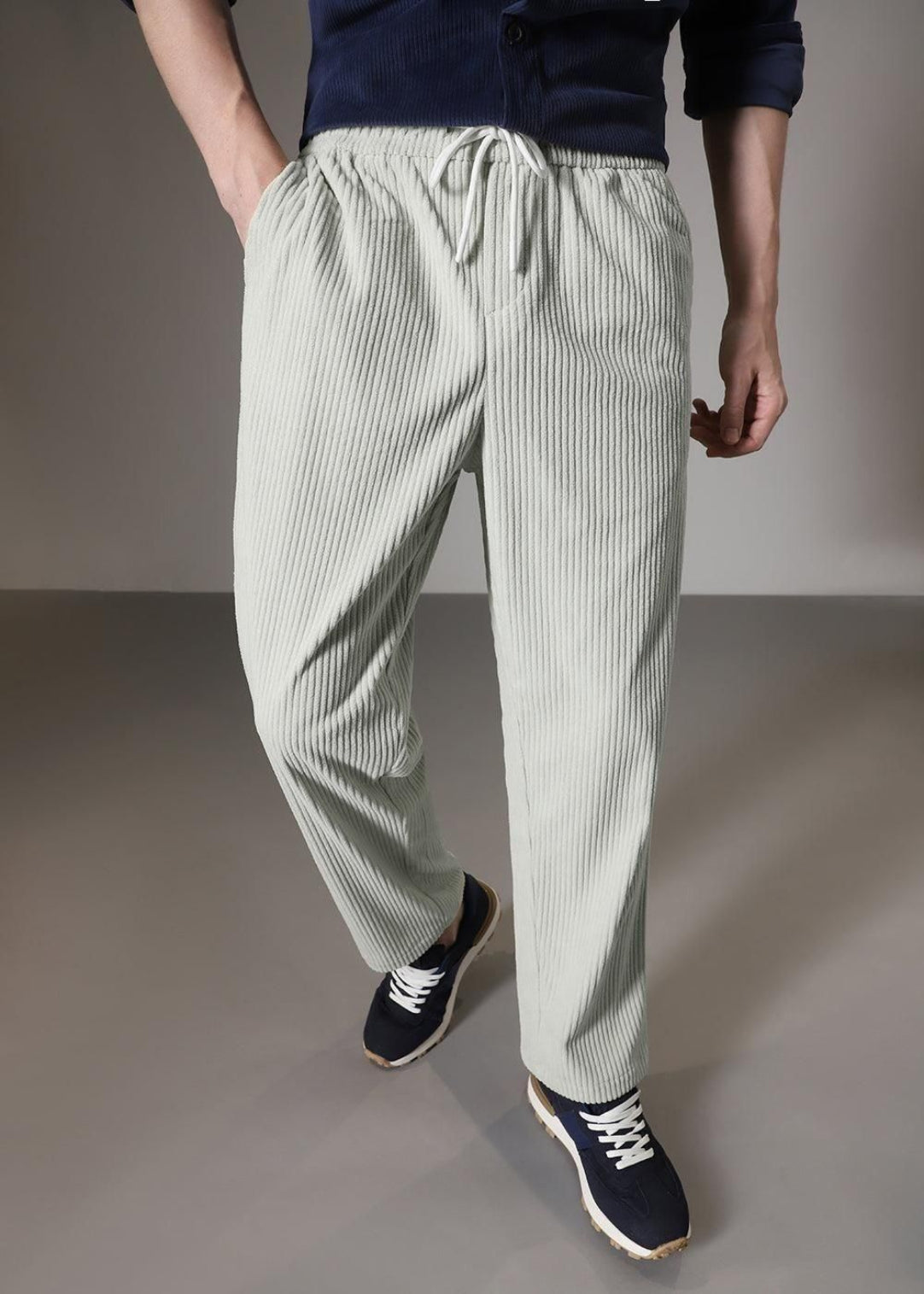 Person wearing light green striped pants on a plain background