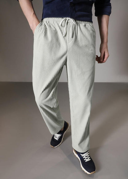 Person wearing light green striped pants on a plain background