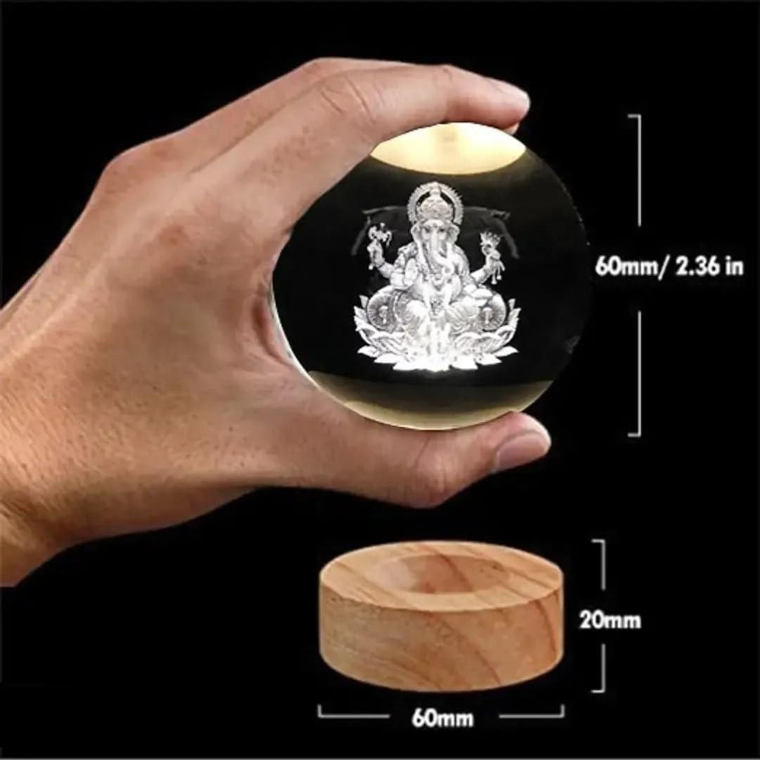 Hand holding a crystal ball with an engraved design, next to a wooden base with measurements.