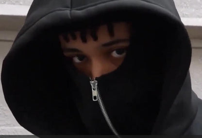 Person wearing a black hoodie with a zipper, partially covering their face.
