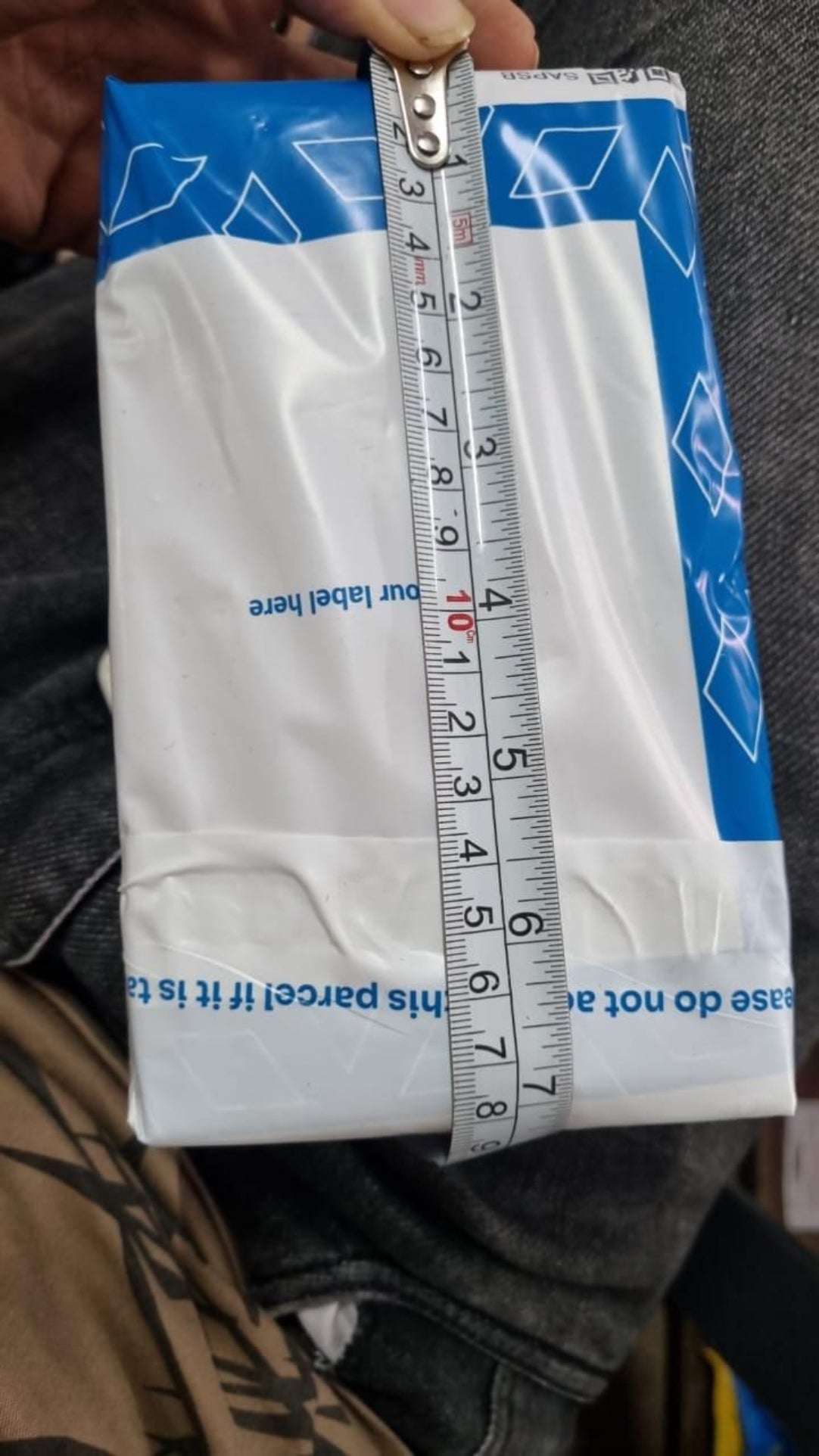 Box of dental floss with a ruler on top, held by a person.