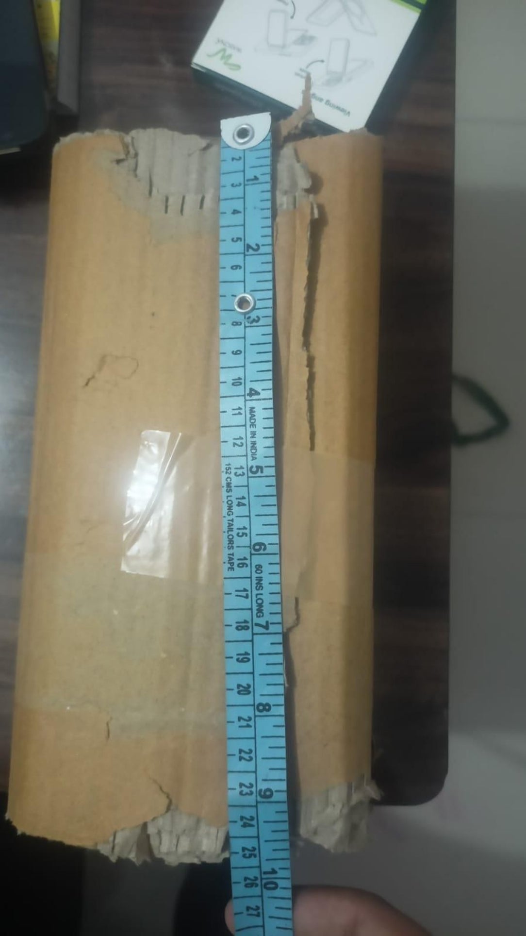 Roll of paper with a ruler for scale on a dark surface