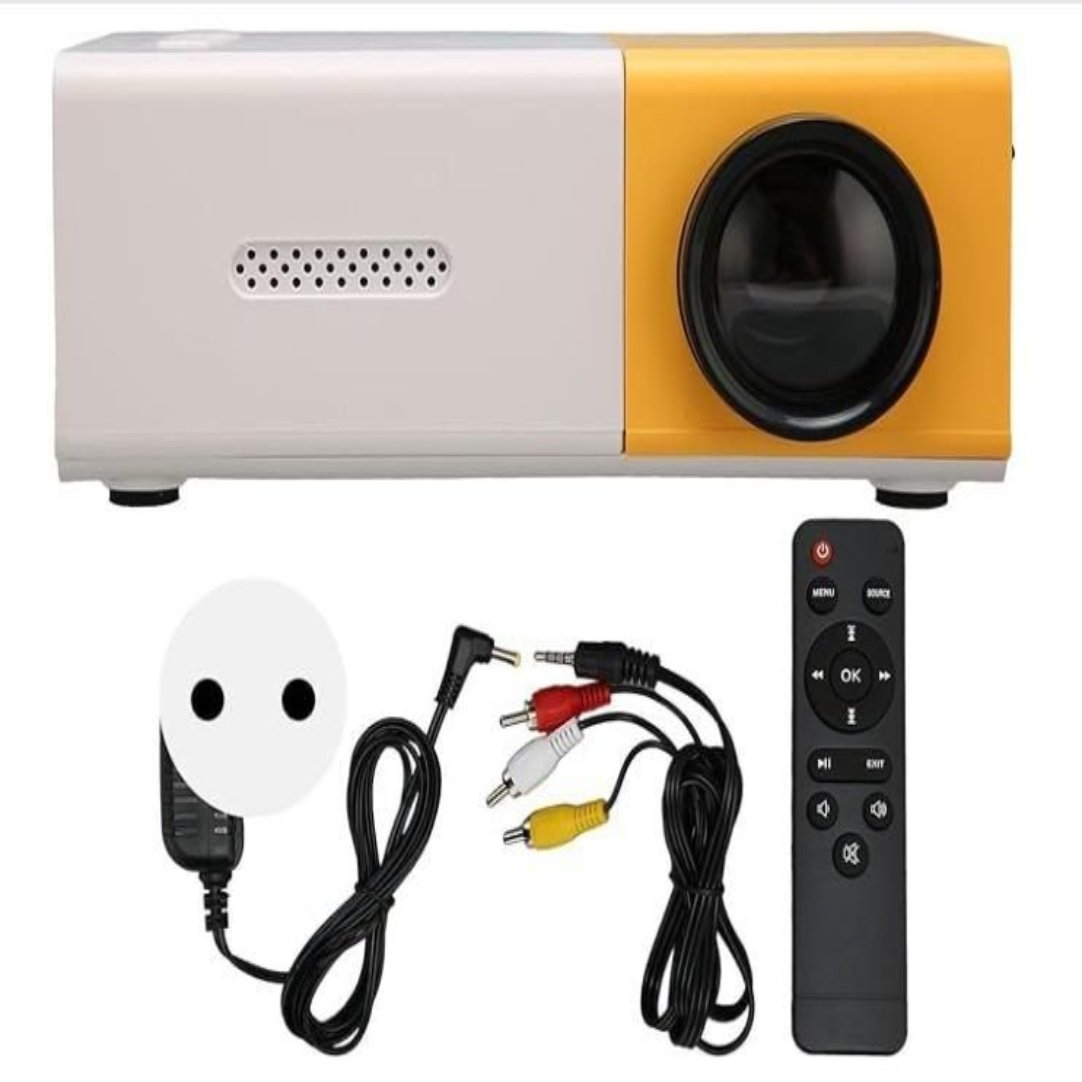A portable mini projector with white and yellow coloring, accompanied by a remote control and cables. The projector has a dome-shaped screen and a speaker grill visible on one side.