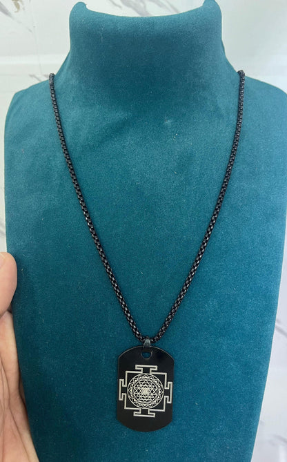 Black chain necklace with a pendant on a teal mannequin