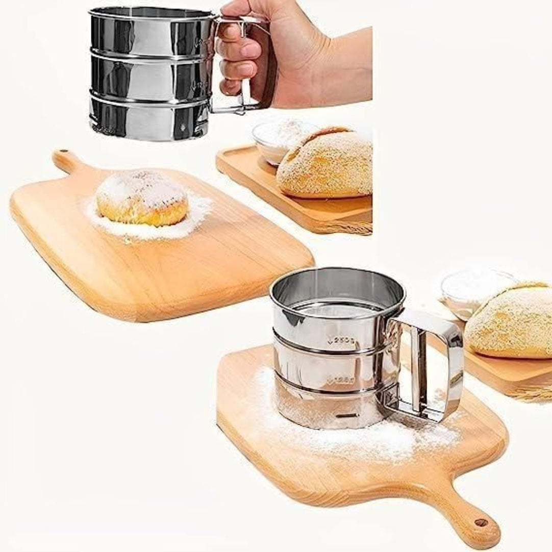 Metal flour sifter on a wooden board with powdered sugar and bread.