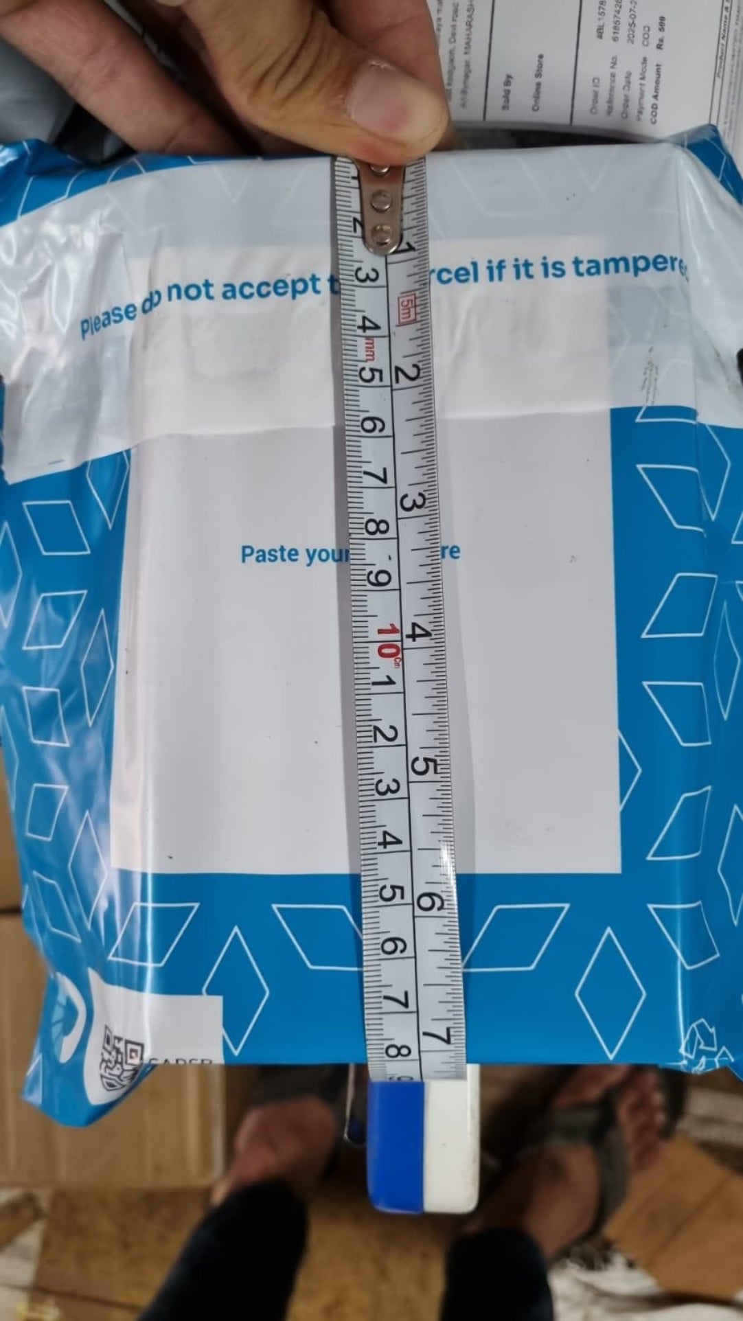 Measurement of a package with a ruler, showing dimensions on a white background.