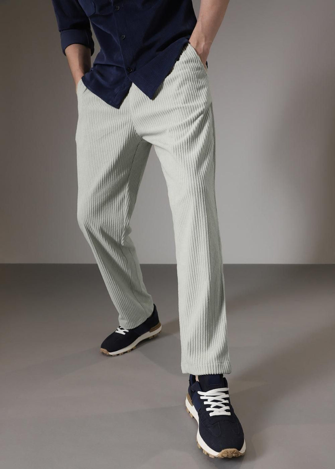 Person wearing light gray striped pants and navy shoes on a plain background