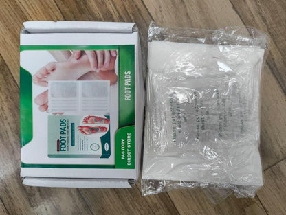 Box of foot pads with a clear plastic bag containing white patches on a wooden surface.