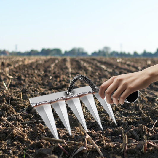 Person holding a gardening tool in a field