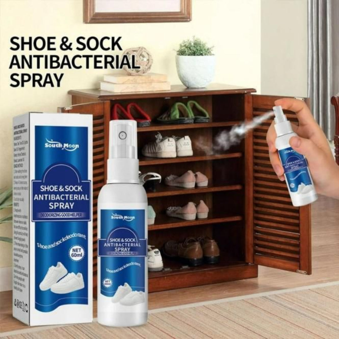 A person's hand spraying a blue bottle of Antibacterial Shoe & Sock Deodorant Spray into a shoe rack filled with various shoes.