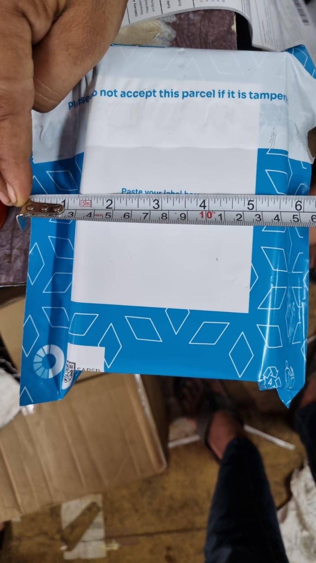 Blue package with a white label being measured with a ruler