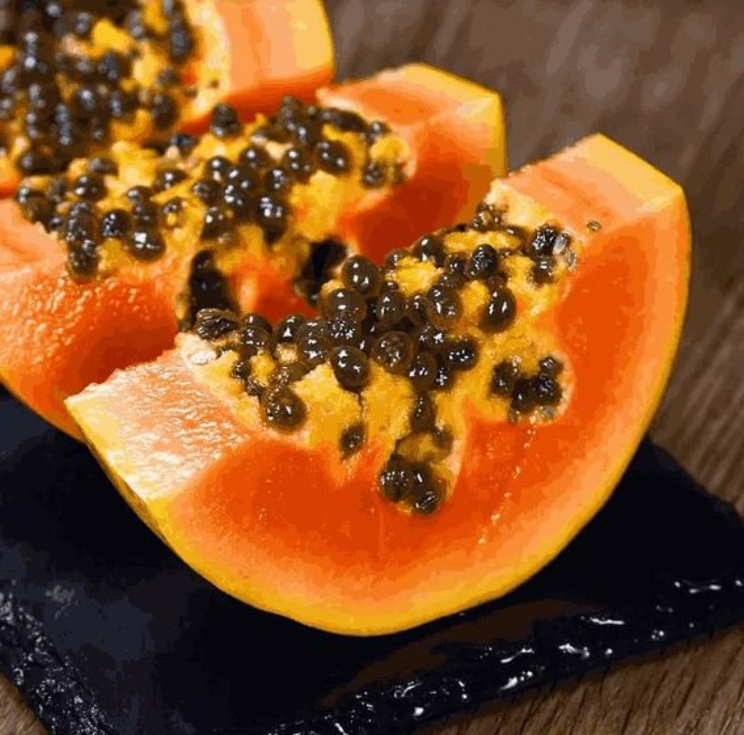 Halved papaya with black seeds on a dark surface