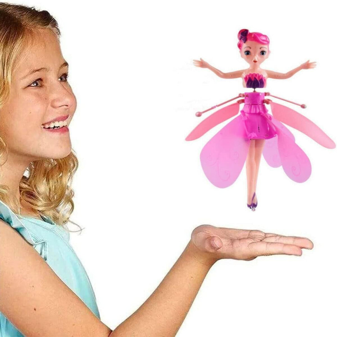 Girl holding a pink fairy toy above her hand with a plain background